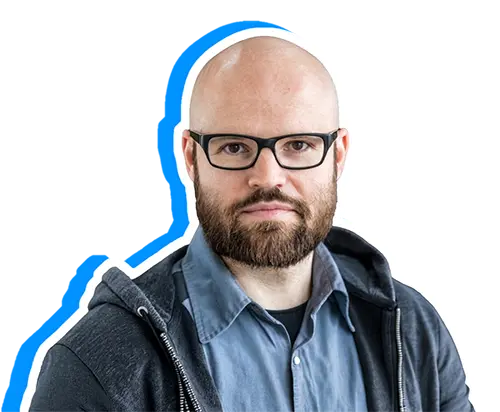 Porträt von Philipp, mit Bart und Brille in einem grauen Hoodie, freigestellt vor schwarzem Hintergrund mit blauem grafischem Umriss